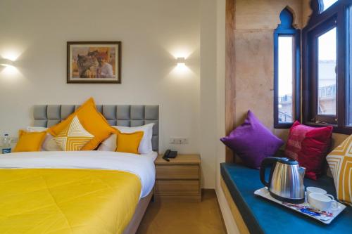 1 dormitorio con 1 cama con almohadas coloridas en Hotel Aradhya Jaisalmer, en Jaisalmer