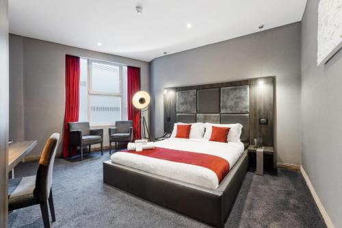 1 dormitorio con 1 cama grande, escritorio y sillas en The Bryson Hotel en Londres