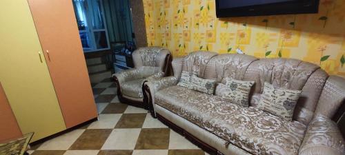 a living room with a leather couch and two chairs at Гостевая комната in Chernivtsi