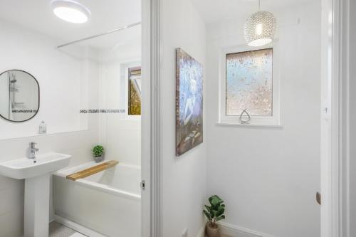 a bathroom with a white tub and a sink and a bath tubermott at Inviting 2-Bed House in Milton Keynes - Netflix in Milton Keynes