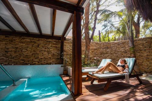 a woman sitting in a chair next to a swimming pool at The Beach Tulum Hotel in Tulum