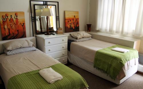 a bedroom with two beds and a dresser with a mirror at 36 Mount Road Guesthouse and Self Catering in Port Elizabeth