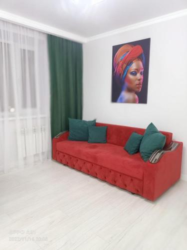 un sofá rojo en una sala de estar con una pintura en Мухтара Ауэзова 205 en Kokshetau