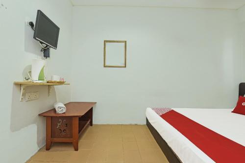 a room with a bed and a table with a tv at OYO 90324 Muar Station Hotel in Kuah