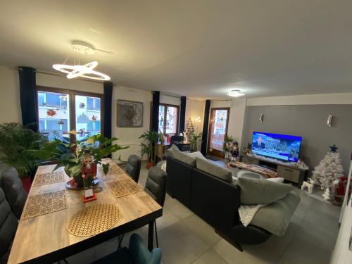 a living room with a table and couch and a television at Mallo's Lodge avec Parking GRATUIT et 2 balcons in Colmar