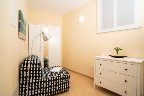 a bedroom with a chair and a dresser with a lamp at Miramar 3 in San Sebastián de la Gomera