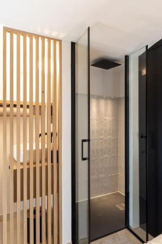 La salle de bains est pourvue d'une porte en verre et d'une douche. dans l'établissement LE M Luxueux appartement sur le Vieux port de Marseille, à Marseille