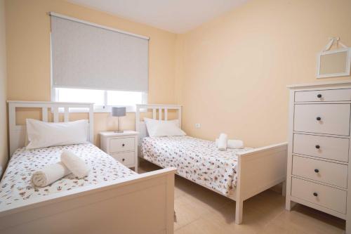 a bedroom with two beds and a dresser and a window at Miramar 4 in San Sebastián de la Gomera