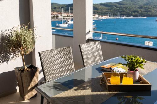 een glazen tafel op een balkon met uitzicht op het water bij Apartments & Rooms Fisherman's Luck in Vela Luka