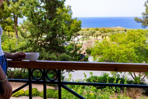 a person standing on a balcony with a bowl on a rail at Korineum Golf & Beach Resort in Kérynia