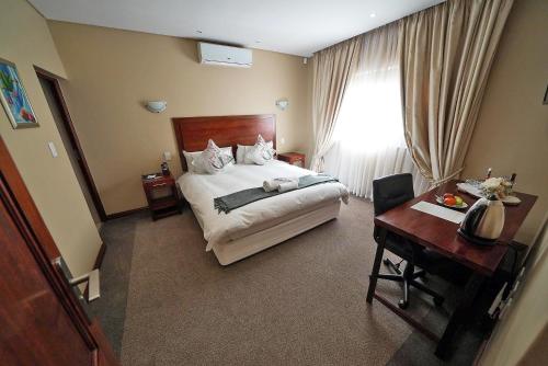 een slaapkamer met een bed, een bureau en een raam bij Over The Moon Guesthouse in Johannesburg