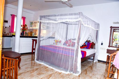 a bedroom with a bed with a canopy at Indika's Apartment in Hikkaduwa