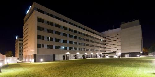 a large building at night with a grass field in front at Axor Feria in Madrid
