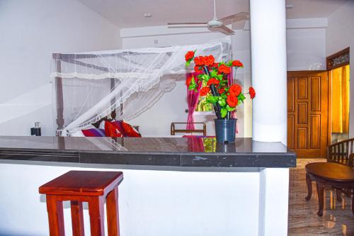 a kitchen with a counter with red flowers in a vase at Indika's Apartment in Hikkaduwa