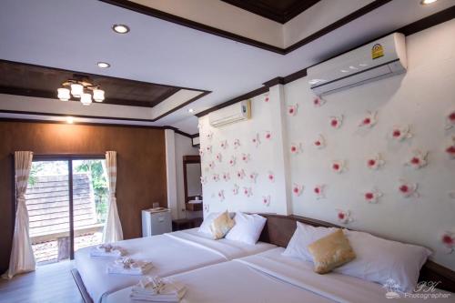 a bedroom with a bed and a wall with flowers at Suanya Kohkood Resort and Spa in Ko Kood