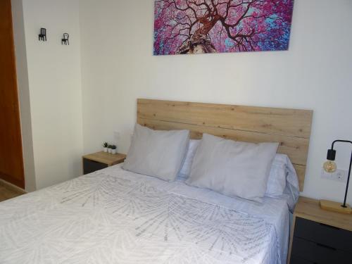 1 dormitorio con 1 cama blanca y una pintura en la pared en Apartamento Dama de Guardamar, en Guardamar del Segura