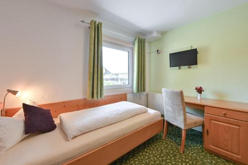 a hotel room with a bed and a desk and a window at Pension Freiheit in Pfronten