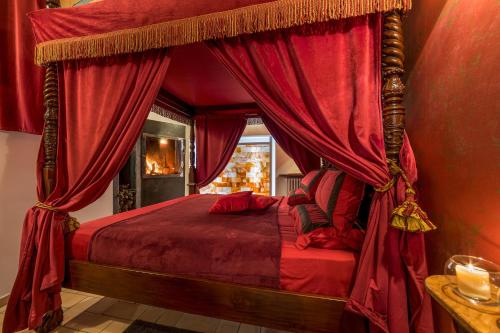 1 dormitorio con cama con dosel y cortinas rojas en Il Confessionale, en Castelnuovo di Porto