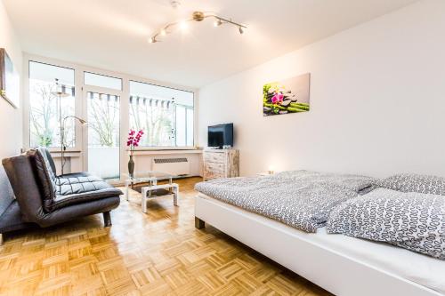 een witte slaapkamer met een bed en een stoel bij Work & Stay Apartment Monheim in Monheim