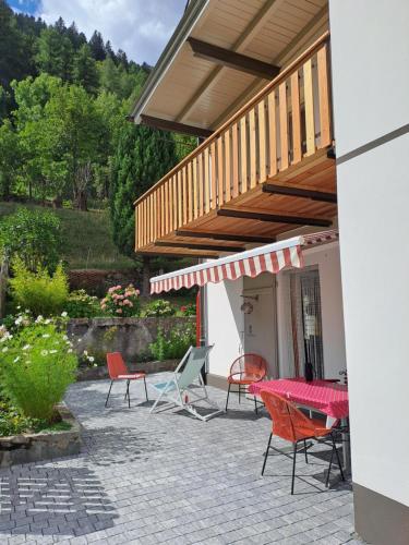 a patio with chairs and a table and a balcony at Appartamento incantevole: CASA SAN PIERU in Poschiavo