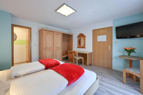 a bedroom with a bed and a table and a television at Pension Freiheit in Pfronten