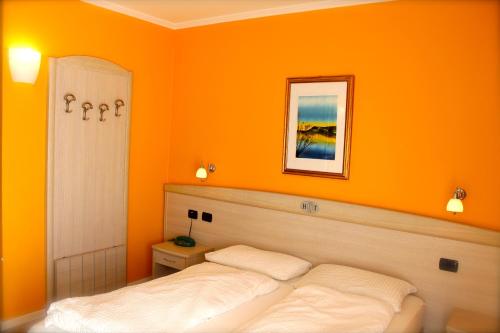 two beds in a room with an orange wall at Hotel Toresela Bike am Gardasee in Nago-Torbole