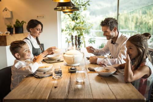 a family sitting around a table eating soup at Luxuslodge - Zeit zum Leben in Annaberg im Lammertal