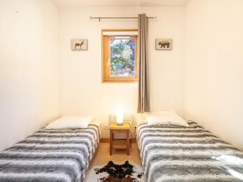 duas camas num quarto com uma mesa e uma janela em Les Bouquetins - 5 - Appart Chaleureux 6 pers em Saint-Sorlin-dʼArves