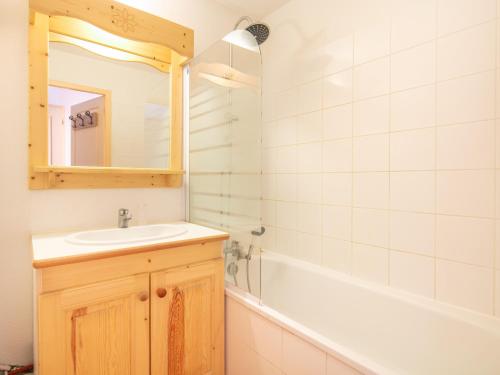 une salle de bain avec un lavabo, une baignoire et un miroir dans l'établissement Les Chevreuils - 71 - Appart lumineux 4 pers, à Saint-Sorlin-dʼArves