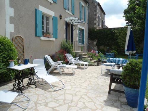 a patio with white chairs and tables and an umbrella at La maison bleue in Arquian