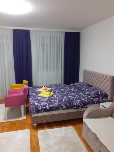 a bedroom with a purple bed and a pink chair at Apartman JOVANA in Vršac