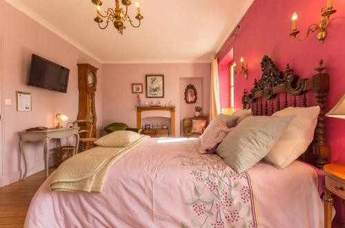 a bedroom with a large bed with pink walls at La maison bleue in Arquian