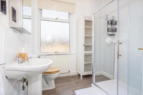 a bathroom with a sink and a toilet and a window at Stylish 3 Bedroom Central Property in Newcastle under Lyme