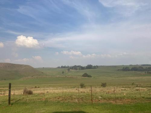 un champ vert avec une clôture au premier plan dans l'établissement Mountain View Farm Cottage 4X4 Vehicles ONLY, à Dullstroom
