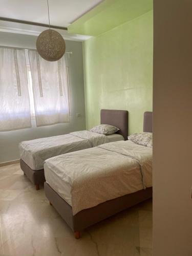 a bedroom with two beds and a window at Airport to Comme à la maison 1 in Nouaseur