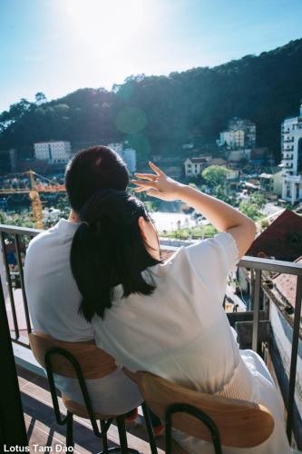a man and woman sitting on a balcony looking at the city at Rosalia Hotel Tam Đảo in Tam Ðảo