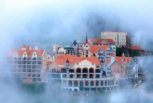 un grand bâtiment avec des toits orange dans le brouillard dans l'établissement Ros Hotel Tam Đảo, à Tam Ðảo