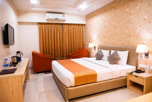 a hotel room with a bed and a desk and a television at Hotel Sagar in Guwahati
