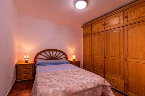 um quarto com uma cama e armários de madeira em 3 bedrooms house at Los Caserones 50 m away from the beach with enclosed garden and wifi em Las Marciegas