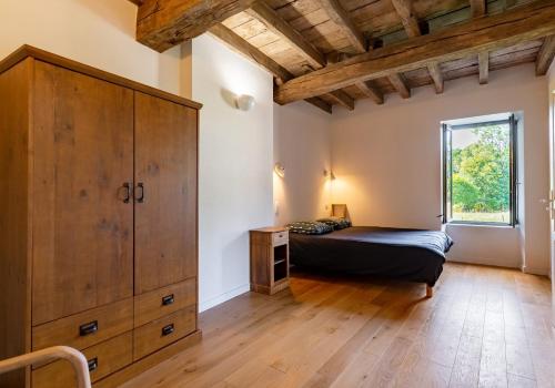 ein Schlafzimmer mit einem Bett und einem großen Holzschrank in der Unterkunft Gîte de l'Abbaye in Brandivy