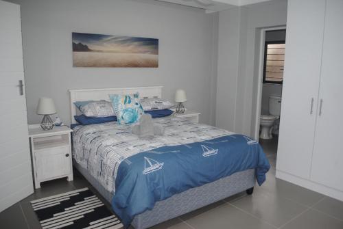 a bedroom with a bed with a blue comforter at Barefoot Bungalo in Amanzimtoti