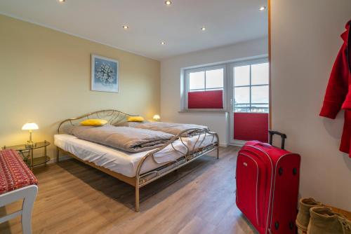 1 dormitorio con 1 cama y 1 maleta roja en Franze´s Haus - mit Rhein- & Burgenblick, en Boppard