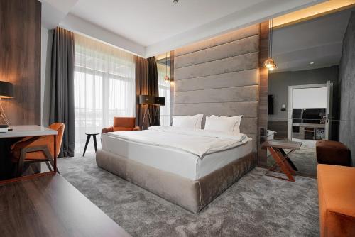 a bedroom with a large white bed and a desk at Hotel Srbija Lux in Stara Pazova