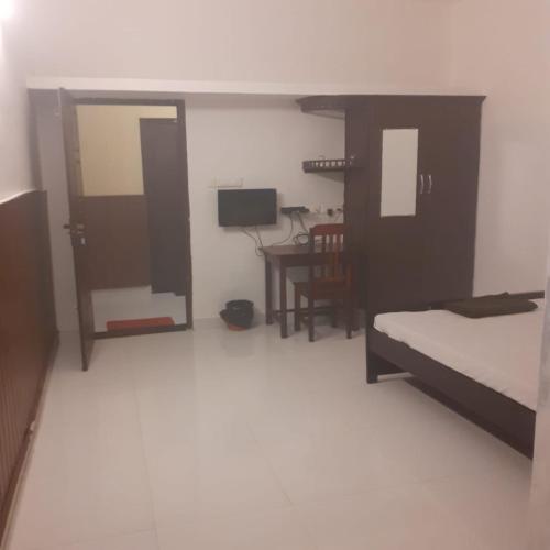 um quarto com uma cama, uma secretária e uma televisão em TABISH inn em Trivandrum