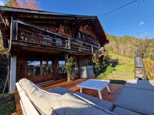 a house with a couch and a table in front of it at Gstaad Paradise View Chalet with Jacuzzi in Rougemont