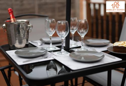 una mesa con copas de vino y platos y un pastel en Lovely Refurbished Home - Free Parking-WiFi By Hinkley Homes Short Lets & Serviced Accommodation en Birmingham