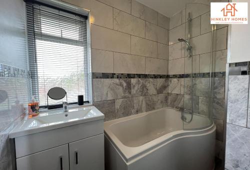 a bathroom with a white tub and a sink at Lovely Refurbished Home - Free Parking-WiFi By Hinkley Homes Short Lets & Serviced Accommodation in Birmingham