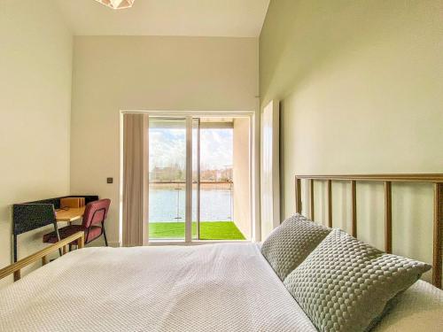 a bedroom with a bed and a view of the water at Linnet Cottage in Somerford Keynes