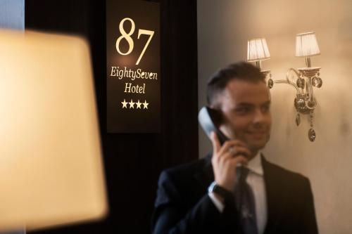 a man in a suit talking on a cell phone at Hotel 87 eighty-seven - Maison d'Art Collection in Rome