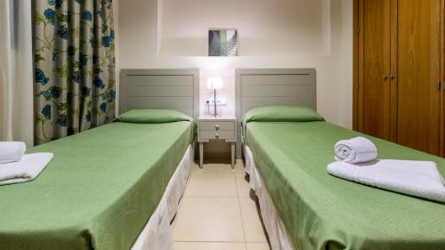 two beds sitting next to each other in a room at Primera Planta Punta Umbria 2 dormitorios junto al mar (1) in Punta Umbría